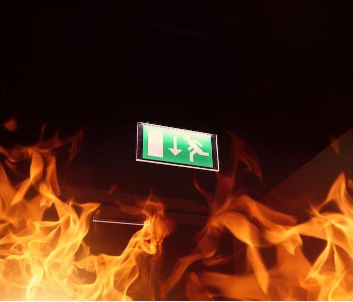 a green fire exit sign above flames from fire